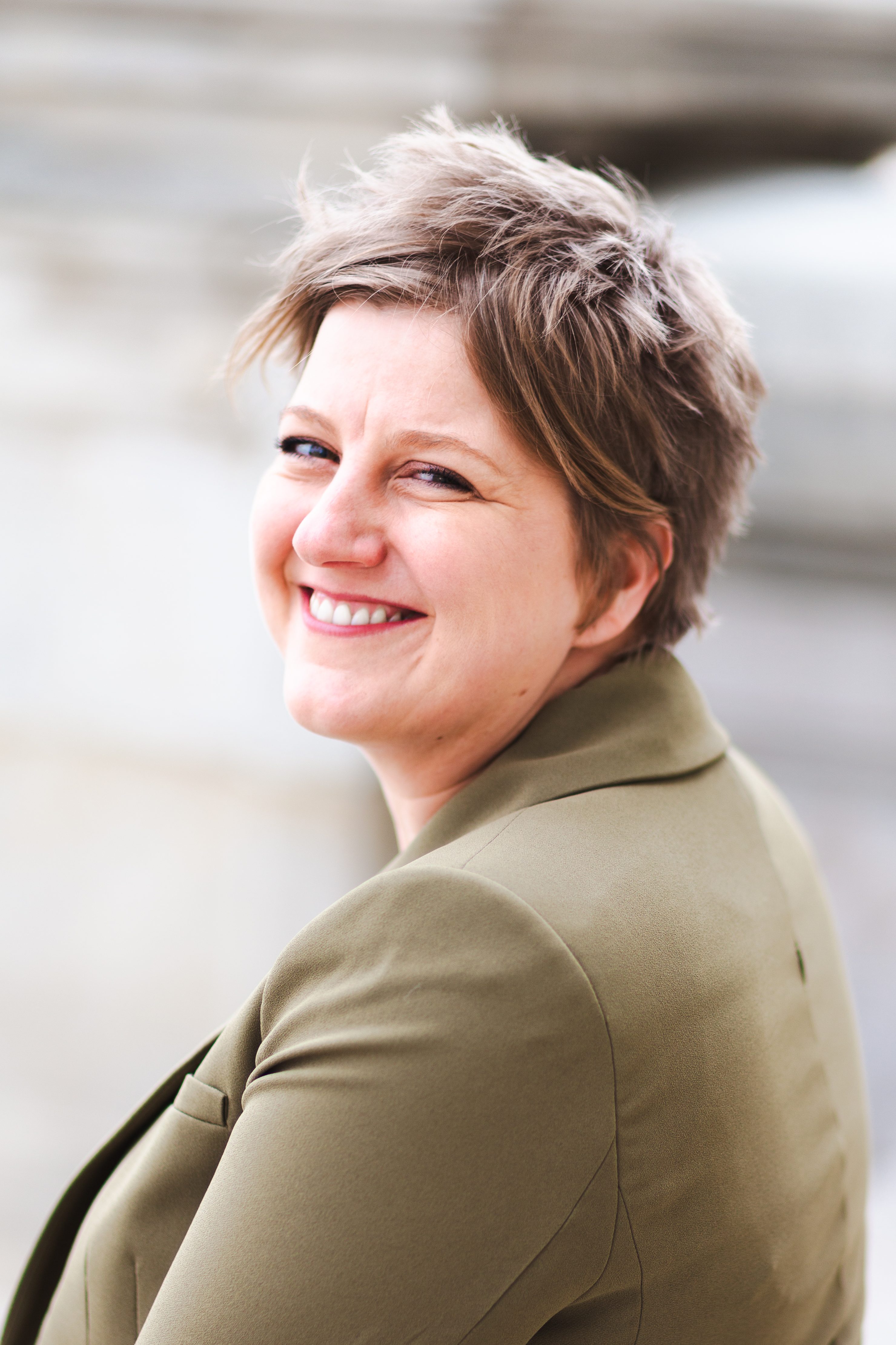 Photo of Jess Blijkers smiling into the camera, wearing a green jacket